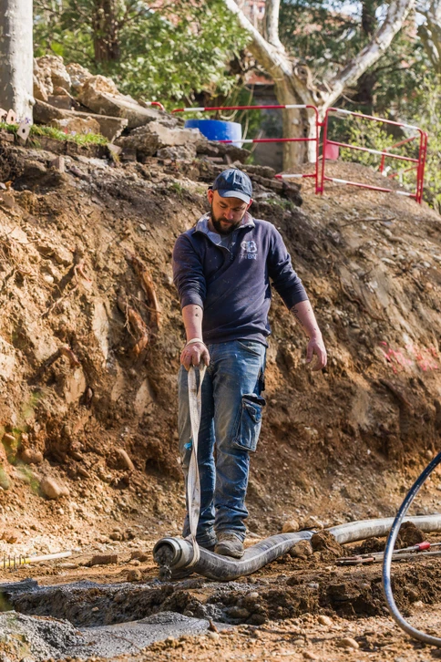 Chantier de construction extérieur où un maçon en vêtements de travail bleus utilise un niveau à bulle jaune pour vérifier l'alignement horizontal d'un mur en cours d'édification