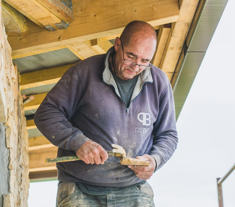 Chantier extérieur de construction, ouvrier installant un ancrage métallique sur poutre béton avec clé à molette
