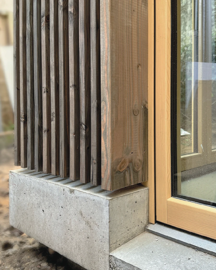 Maison contemporaine plain-pied avec façade en pierre de taille dorée, toiture courbe en bardage métallique brun, menuiseries aluminium gris anthracite