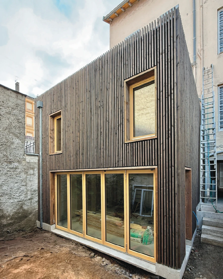 Maison individuelle contemporaine, vue extérieure, façade en enduit gris clair, toiture en tuiles canal avec panneaux solaires