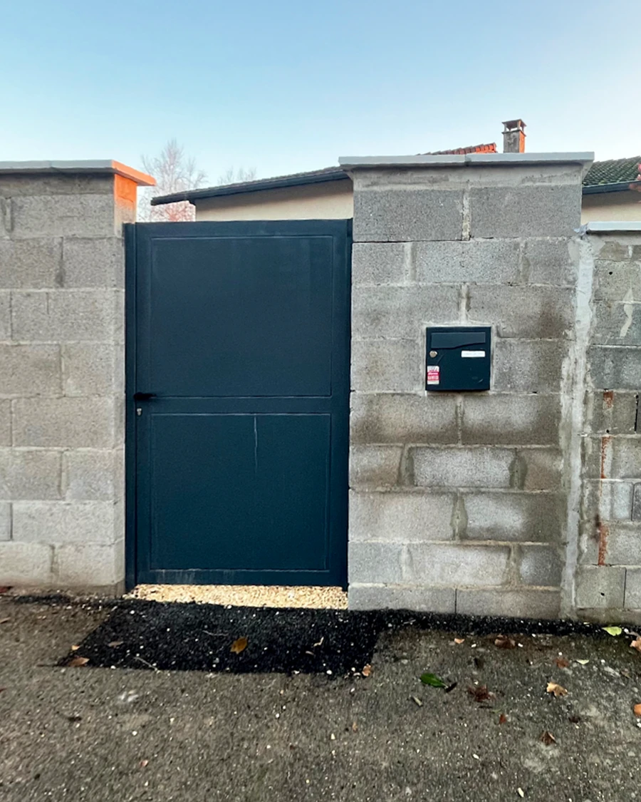 Mur extérieur en béton fissuré avec importantes lézardes verticales, surface dégradée présentant traces d'humidité et effritement