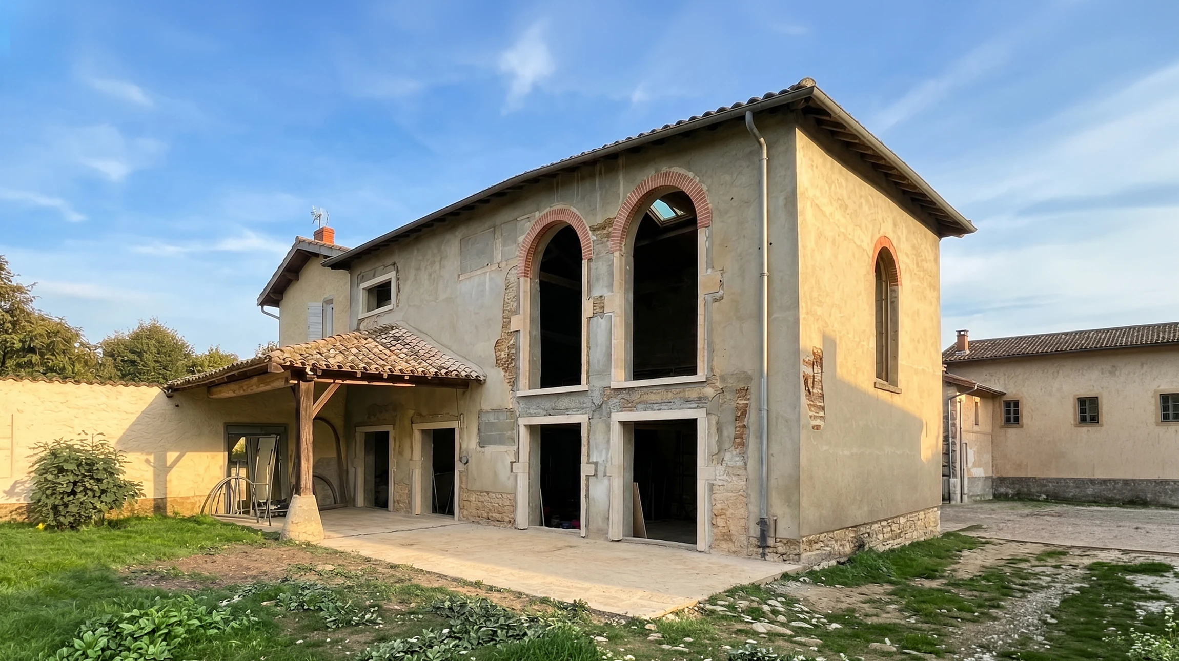 Façade extérieure d'une maison avec fissures importantes sur mur crépi beige et débord de toit