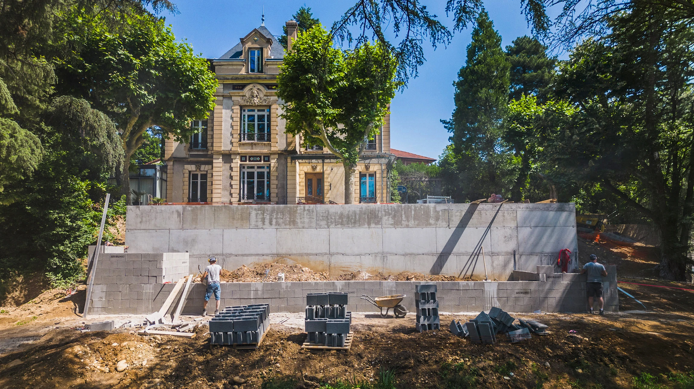 Chantier de construction extérieur avec maçon posant des briques en terre cuite rouge sur un mur